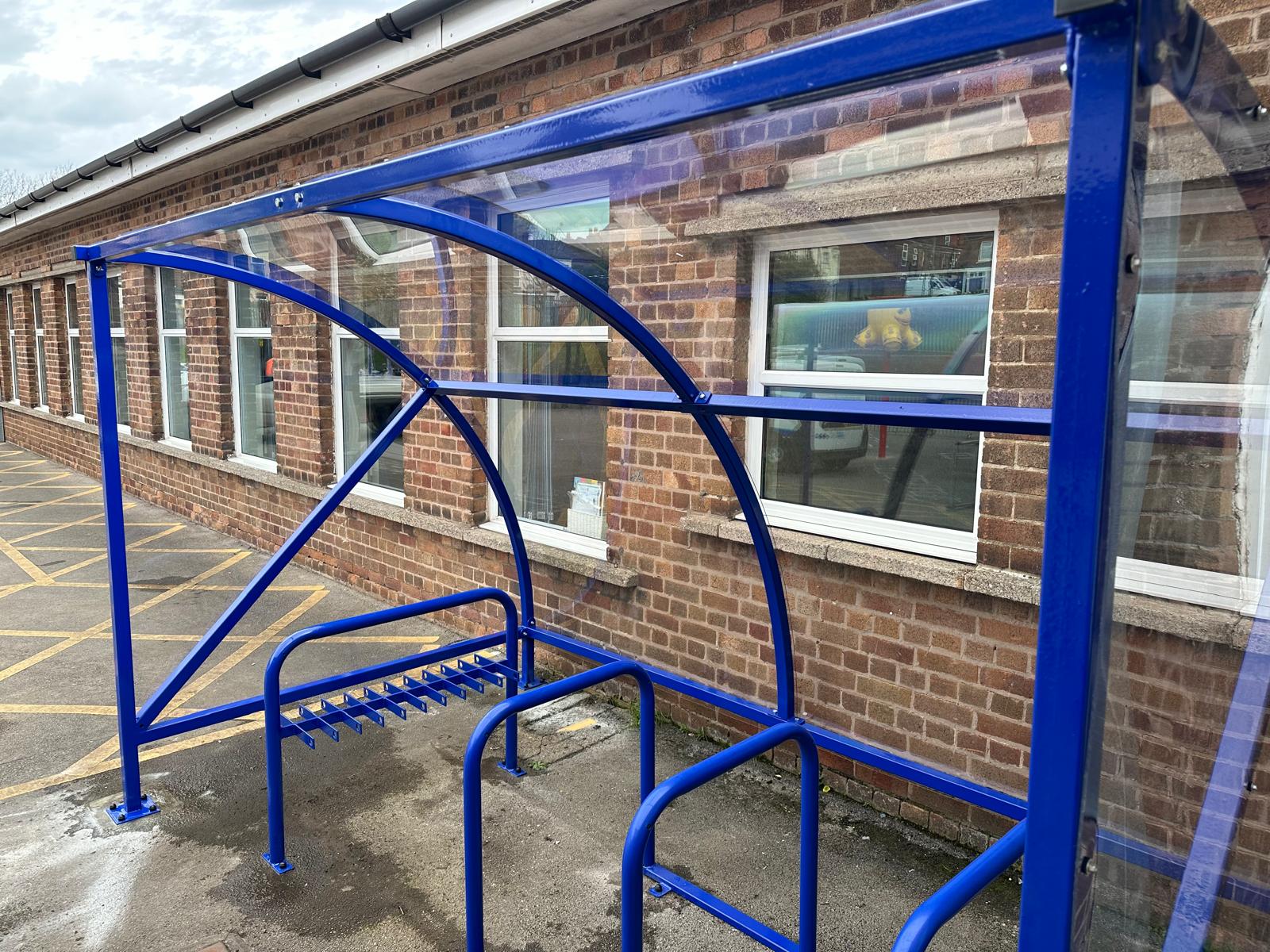 Curved cycle shelter called “The Rosie” featuring sleek curved roof and steel frame