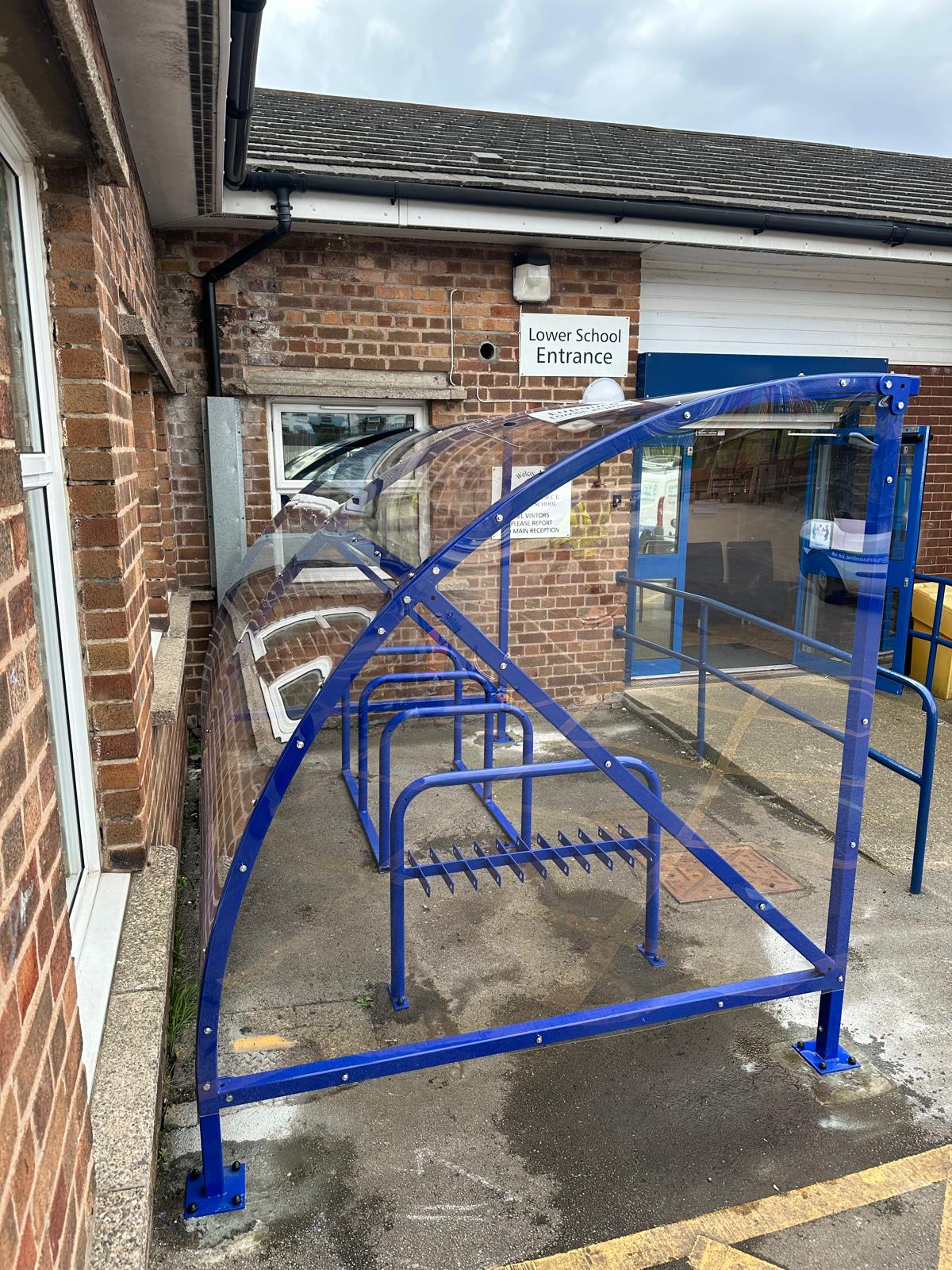 Curved cycle shelter called “The Rosie” featuring sleek curved roof and steel frame